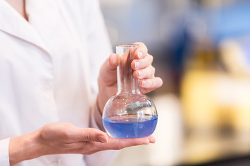 Beaker with liquid in the hands of women scientific