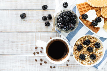 Healthy delicious Breakfast early in the morning: granola cereal, berries, hot black coffee, fresh waffles on the old wooden white background. Top view.