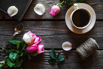 Fresh roses with diary and cup of coffee on wooden table, top view. flowers, hot drink