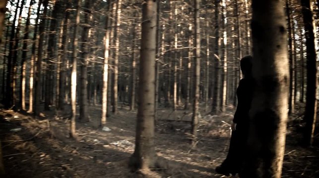 Woman in black walking through the dark haunted forest