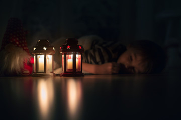 Beautiful little boy, lying down on the floor, looking at candle
