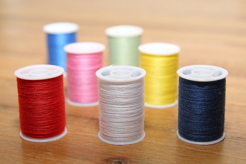 Multi-colored cotton reels or bobbins on a wooden sewing table