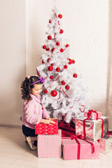 Obraz na płótnie Canvas Child with gift box near white Christmas tree