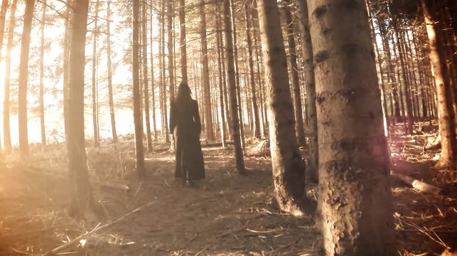 Horror scene. Woman in black walk through the woods