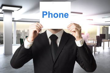 businessman hiding face behind sign phone