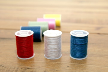 Multi-colored cotton reels or bobbins on a wooden needlework tab