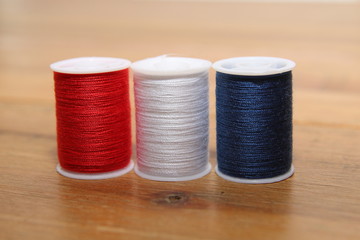 Red white and blue cotton reels or bobbins on a wooden needlewor