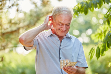 Alter Mann mit Tabletten blickt unsicher