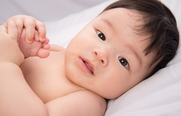 Portrait of cute Little asian boy 6 months old on the white bed