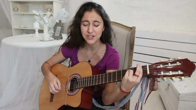Girl in a white shirt plays guitar in classic style
