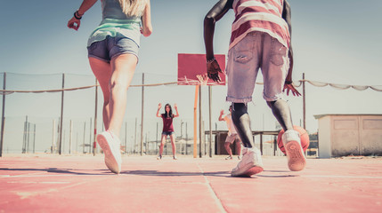 Group of multiracial friends playing basketball togheter.