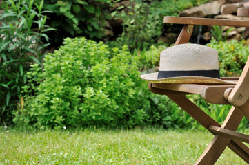 chapeau en paille sur chaise de jardin