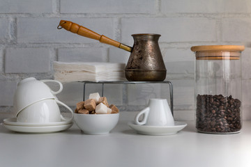 Coffee drink concept. Coffee cups, jezve, coffee beans, sugar cubes, cane sugar, white sugar and white porcelain cups. Piece of coffee restaurant interior.