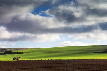 Naklejka premium tracteur dans les champs sous un ciel d'automne