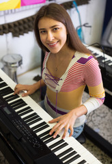 Girl choosing synthesizer in store.