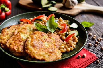 Roasted pork cutlets coated in cheese and breadcrumbs, served with chick peas and vegetable