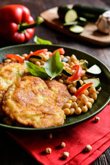 Roasted pork cutlets coated in cheese and breadcrumbs, served with chick peas and vegetable