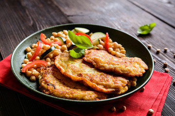 Roasted pork cutlets coated in cheese and breadcrumbs, served with chick peas and vegetable