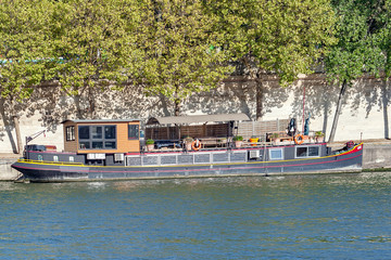 Fototapeta na wymiar PARIS, FRANCE, April 25, 2016. A Barge on the Seine in Paris. It is very common to see these beautiful boats that serve as housing on the Seine River in Paris