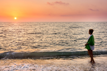 Fototapeta na wymiar Adult woman on the beach at sunset in sea