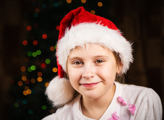 Lovely girl in a Christmas hat on festive background
