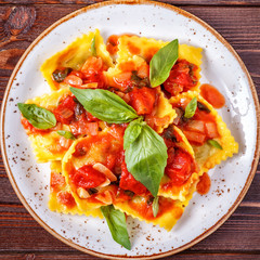 Ravioli with tomato sauce and basil on dark background.