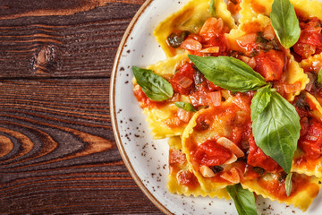 Ravioli with tomato sauce and basil on dark background.