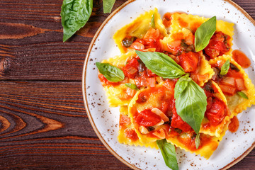 Ravioli with tomato sauce and basil on dark background.