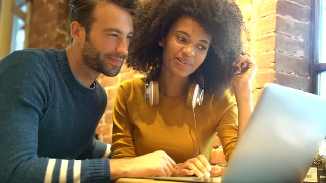 Couple in restaurant connected on internet with laptop