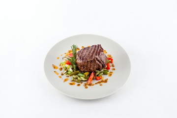 Steak on the grill and a vegetables  garnish on a white background
