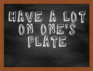 HAVE A LOT ON ONES PLATE handwritten text on black chalkboard