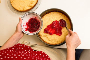 Eine Frau bereitet eine Torte mit Himbeermarmelade auf