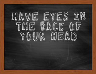 HAVE EYES IN THE BACK OF YOUR HEAD handwritten text on black cha