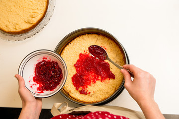 Eine Frau bereitet eine Torte mit Himbeermarmelade auf