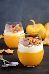 Pumpkin dessert with yogurt and homemade granola on dark wooden table, selective focus, copy space