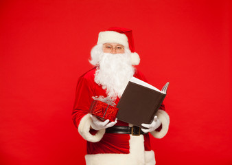 Santa Claus reads old book, on a red background. Christmas