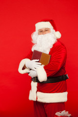 Santa Claus reads old book, on a red background. Christmas