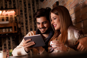 Beautiful young couple looking at tablet in cafe.