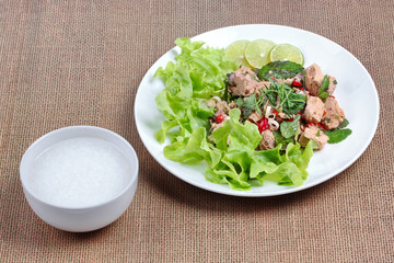 Rice gruel and spicy  vegetable salad with canned tuna served .