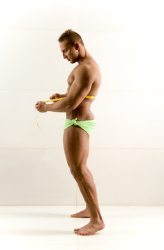 a semi-nude bodybuilder with a measuring tape around his waist
