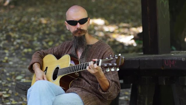 Man playing acoustic guitar outdoors;  real people; 