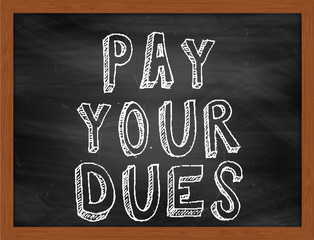 PAY YOUR DUES handwritten text on black chalkboard