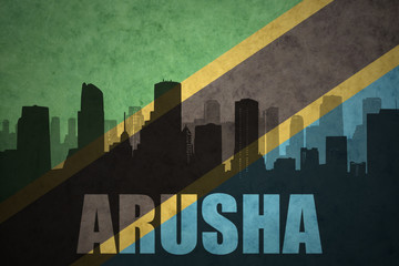 abstract silhouette of the city with text Arusha at the vintage tanzanian flag