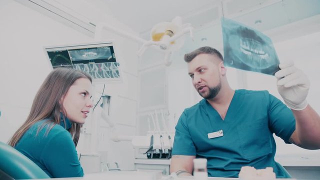A dentist holding an x-ray and explained to the patient. Dentistry. Health. Dental treatment. Modern dental clinic. Orthodontist tells the patient about the wisdom teeth
