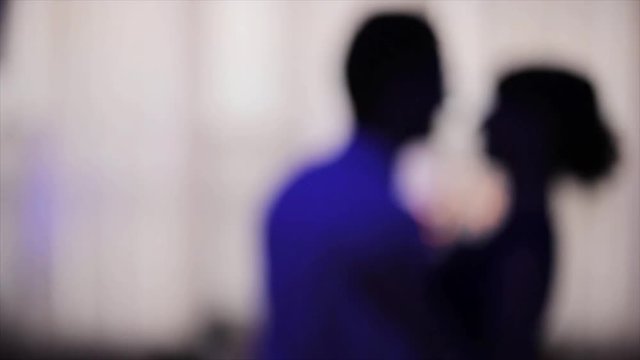 Dancing at night blurred silhouetted couple motion background close up. Man and woman happily fast perform moving together. Two anonymous persons on dance-floor unfocused in neon light