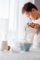 Child preparing cookies in kitchen