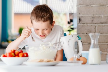 Obraz na płótnie Canvas Child preparing cake and tasting dough in domestic kitchen