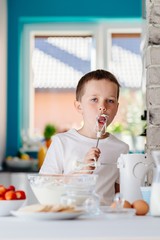 Child tasting pastry from mixer agitator