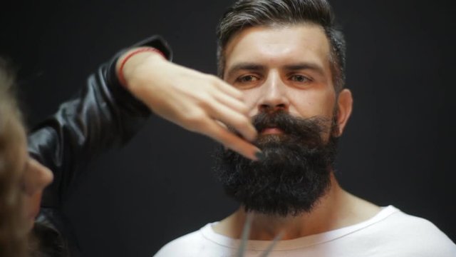 Girl forming beard and mustache style to a man