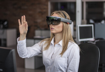 Young woman wearing virtual reality device. Headset. Glasses with virtual screen. Girl touch something using modern glasses with virtual screen. 